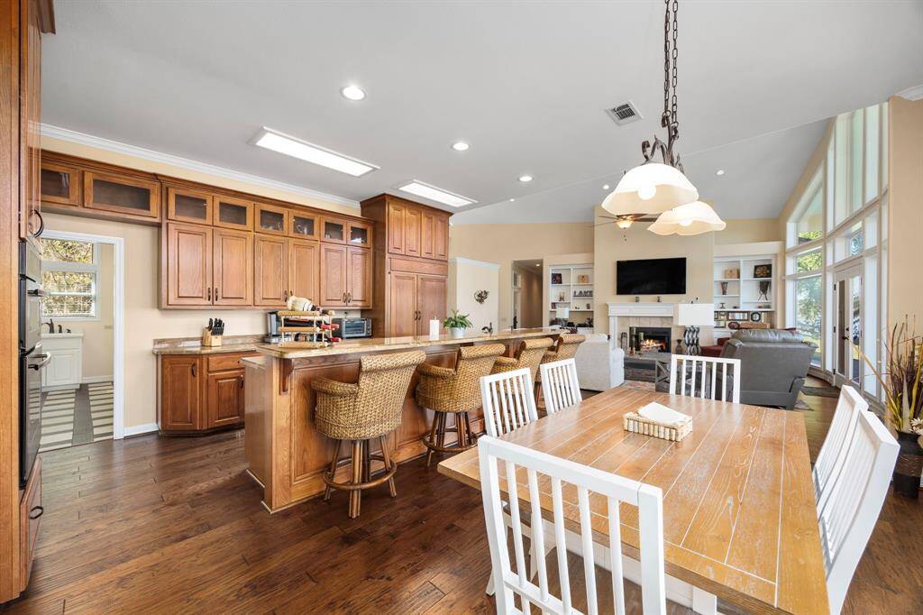 The kitchen is a chef’s dream, featuring custom cabinets, high-end appliances, and a built-in refrigerator for seamless style and function. The adjacent dining area is bathed in natural light, with floor-to-ceiling windows offering sweeping views of the waterfront and the boathouse, creating a perfect space for dining with a scenic backdrop.