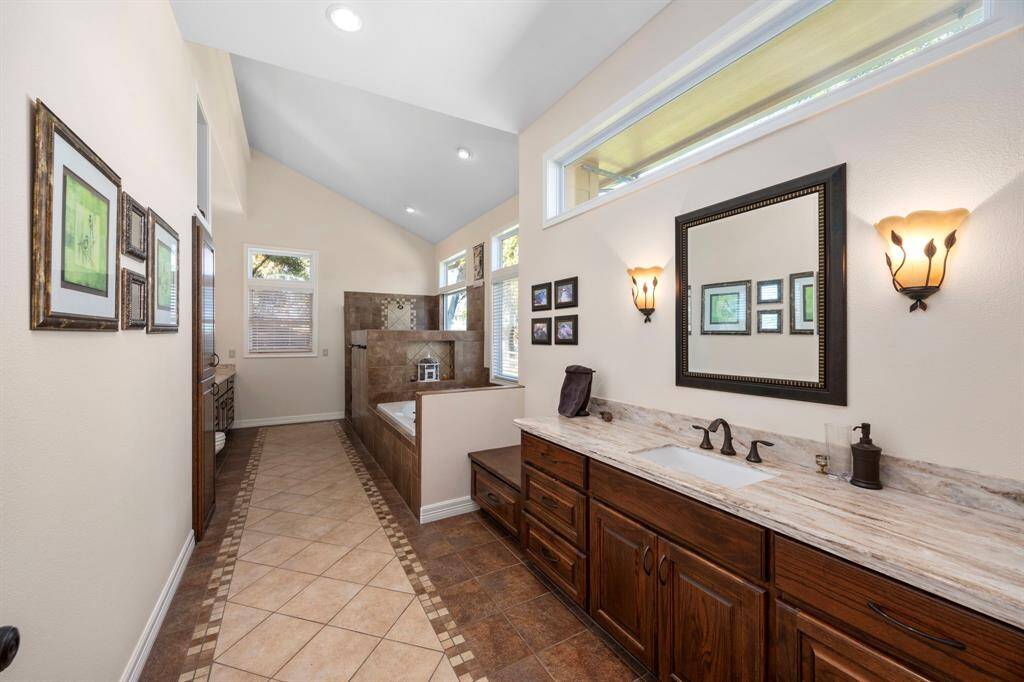 The large primary en-suite bathroom features expanded dual vanity areas, a soaking tub, a spacious walk-in shower, transom windows, custom hardware, and ample storage, creating a perfect blend of luxury and functionality.