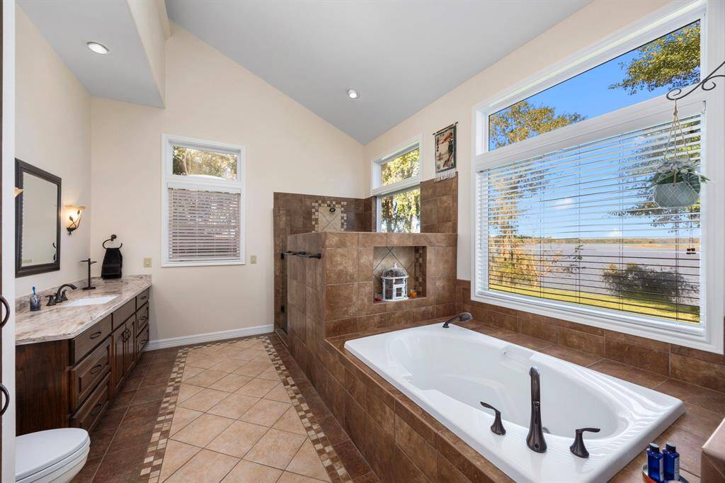 The primary en-suite bathroom boasts a soaking tub with a serene view of the waterfront.  A perfect place to relax and enjoy stunning views with personal privacy.
