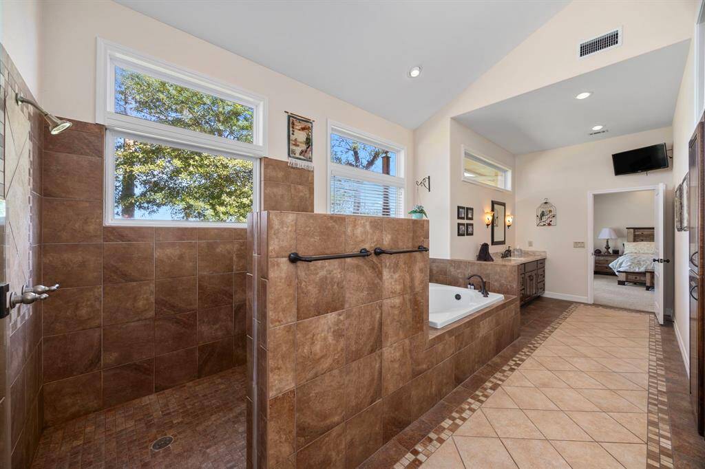 The spacious primary bathroom is designed for ultimate relaxation, featuring a large walk-in shower, a deep soaking tub, and windows that frame breathtaking views of the waterfront at the back of the home.