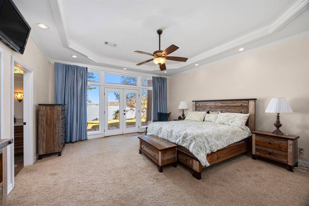 The spacious primary bedroom features French doors that open onto the back deck, offering stunning views of the waterfront, while a tray ceiling with added lighting enhances the room’s elegance. It also includes a large en-suite bathroom and a generous walk-in closet, providing a perfect retreat for both comfort and functionality.