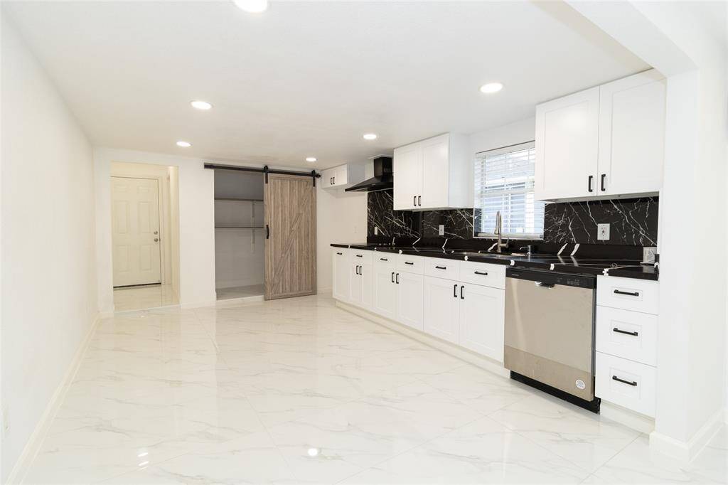 The kitchen features stainless steel appliances and neutral-toned cabinetry.