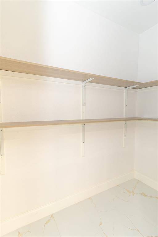 This is a clean, empty walk-in pantry featuring wall-mounted shelves for ample storage space.