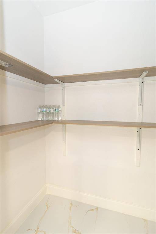 This is a clean, empty walk-in pantry featuring wall-mounted shelves for ample storage space.