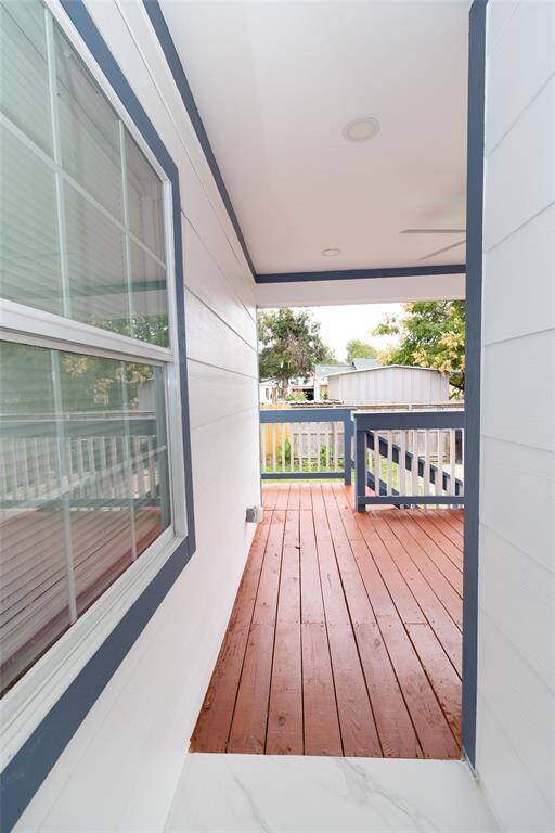 Access to the  cozy covered porch with wooden flooring and white ceiling.