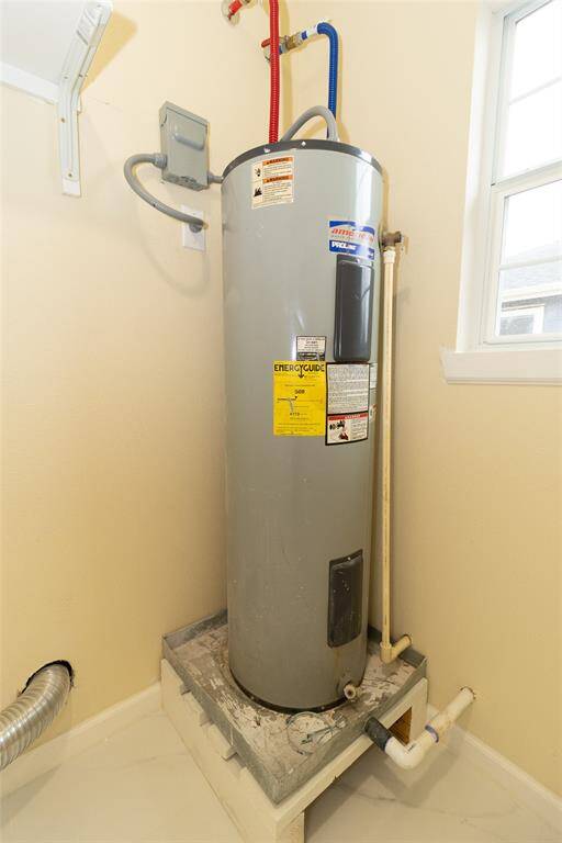 This photo shows a electric water heater located in a utility space with necessary plumbing and electrical connections.