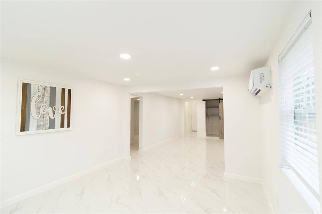 The living room is well-lit with natural light from a window with blinds.