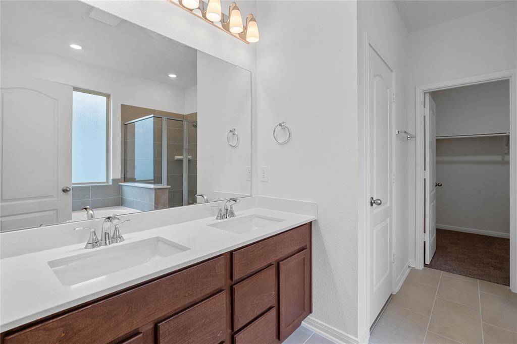 This primary bathroom is definitely move-in ready! Featuring stained cabinets with light countertops, dual vanities, high ceilings, neutral paint, walk-in closet, sleek and modern finishes.