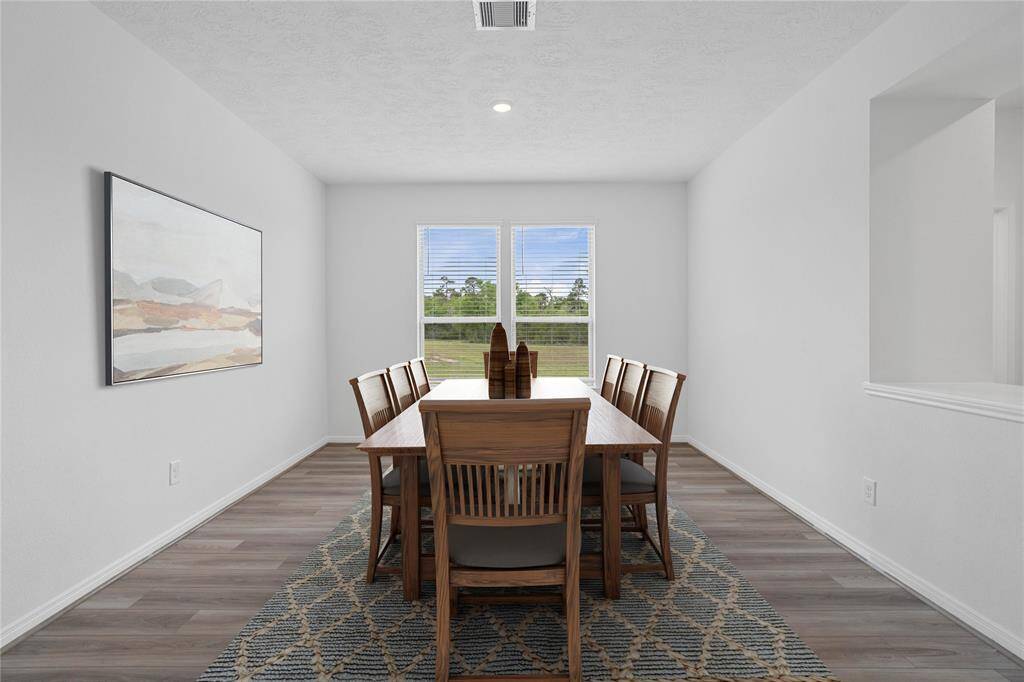 The flex space pictured here is used as a formal dining room featuring vinyl plank flooring, high ceilings, large windows with privacy blinds and neutral paint.