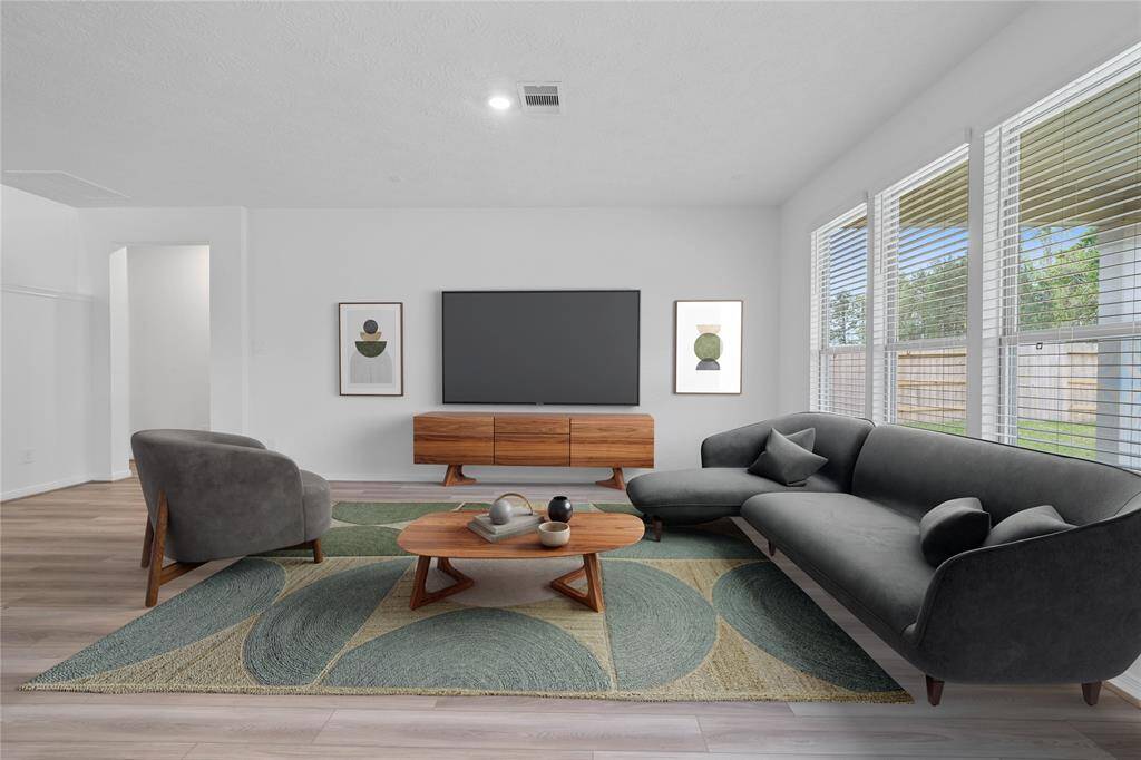 This light and bright spacious family room is the perfect layout for entertaining or just relaxing. Whether it's simply a night in or entertaining family and friends, this home has ample open space for everyone to enjoy! Featuring vinyl plank flooring, large windows with privacy blinds, high ceilings, recessed lighting and custom paint!