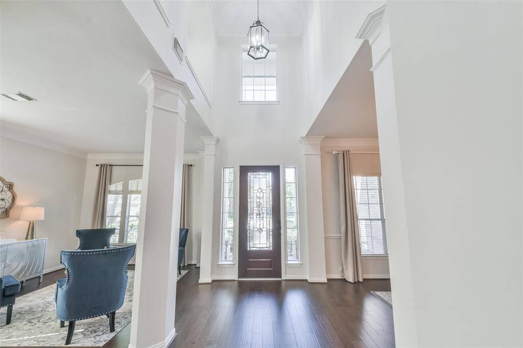 Look at the dramatic entry with 8’ wood front door with leaded glass inserts, wood floors, contemporary light fixtures, and two staircases with wood treads.