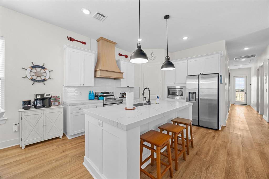Gorgeous quartz countertops and wood laminate flooring make this kitchen so inviting.