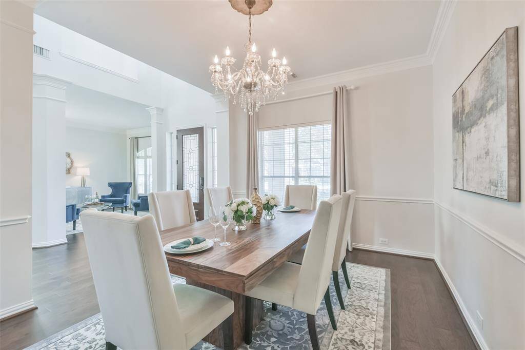 The dining room has wood floors, a chair rail, a stunning chandelier with decorative ceiling medalion, double crown molding, custom drapes, 2” blinds, and built-in shelves for display of china/collectibles.