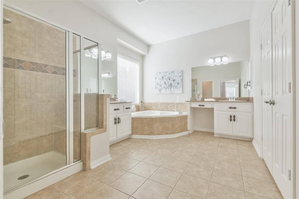 The primary bath has tile floors, a jetted tub, and a shower with bench seating.
