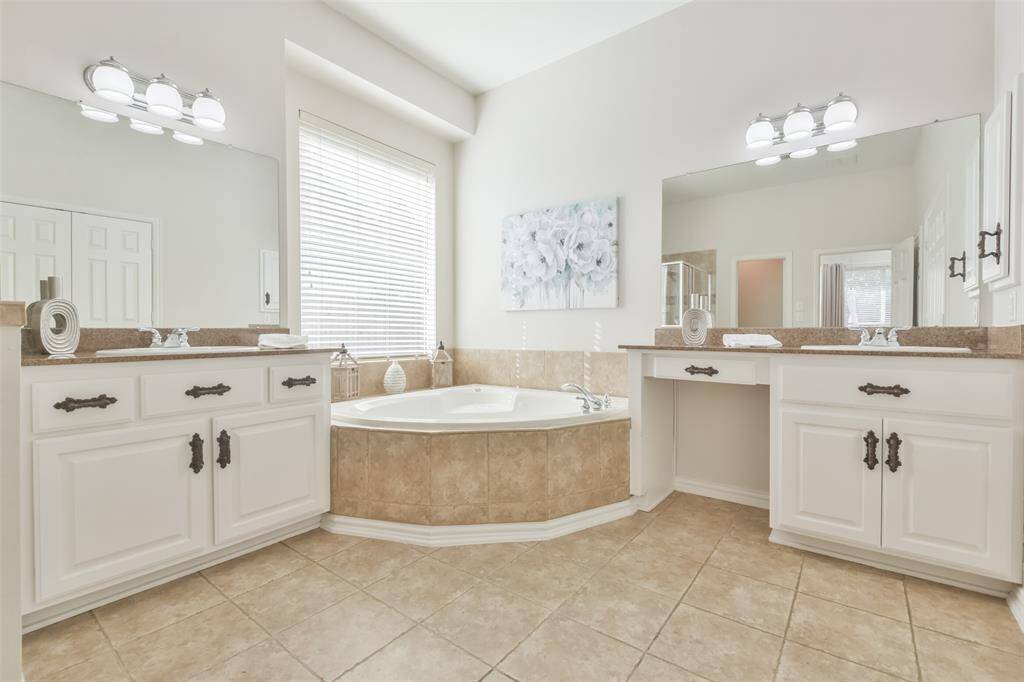 The room also includes granite-topped vanities with double sinks and drawer pulls, contemporary light fixtures, and 2” blinds for privacy.
