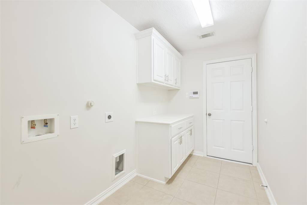 The utility room has tile floors, cabinets with drawer pulls and a door leading to the 2-car garage.