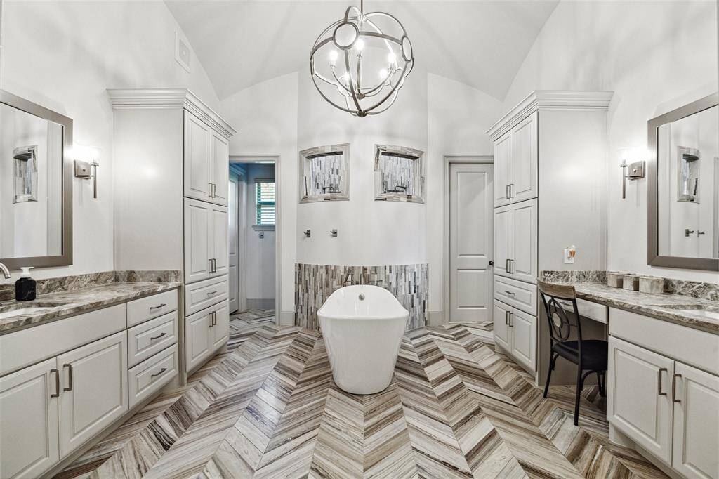 The centerpiece of the primary bathroom is the massive shower, offering a spa-like experience with multiple shower heads, seating, and luxurious finishes.