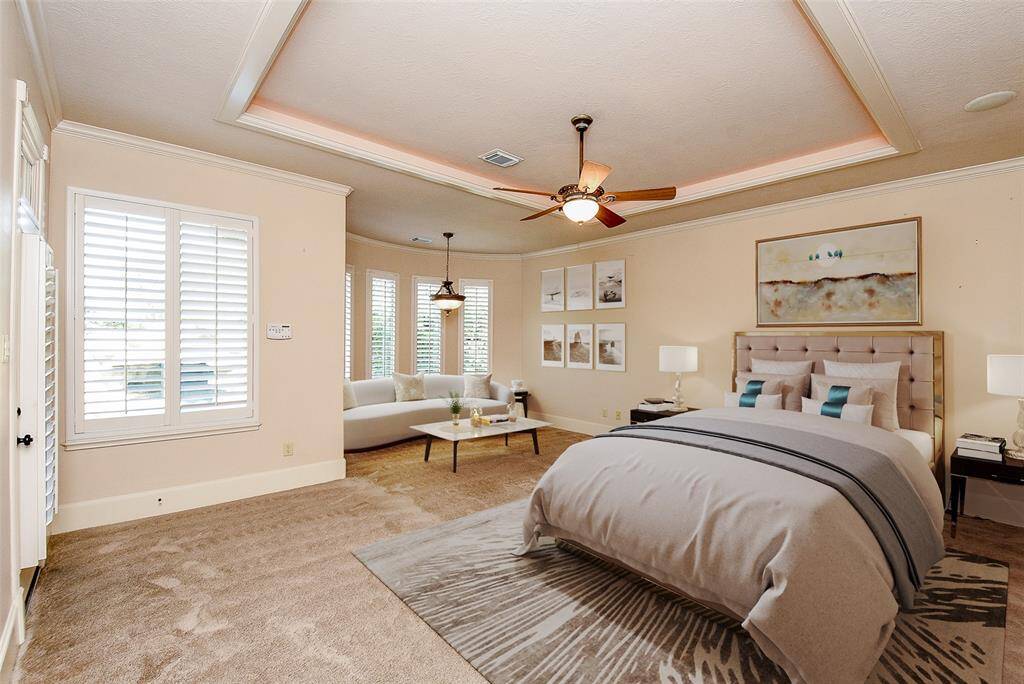 The Primary Bedroom is very spacious and has a nice sitting area nook that overlooks the pool, lake and beautifully landscaped backyard.  There is also a side door to lead out to the pool for those midnight swims.  This photo is virtually staged.