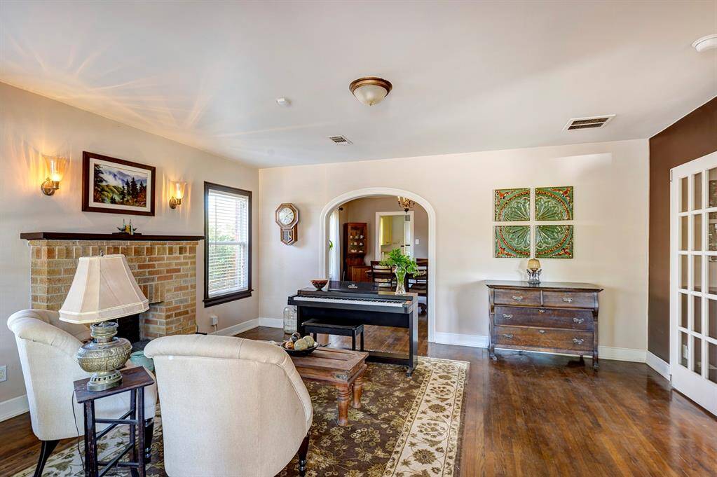 Bright living room with gleaming hardwoods and mock fireplace.
