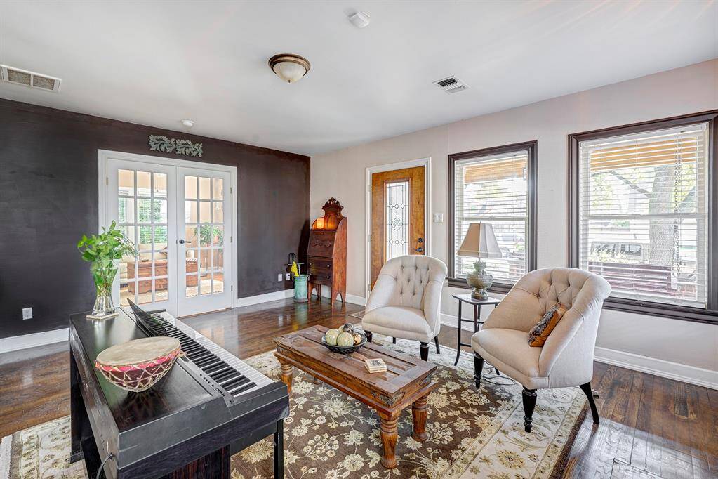 Another view of living room with casement windows and coverings. French doors lead to sitting room or third bedroom.