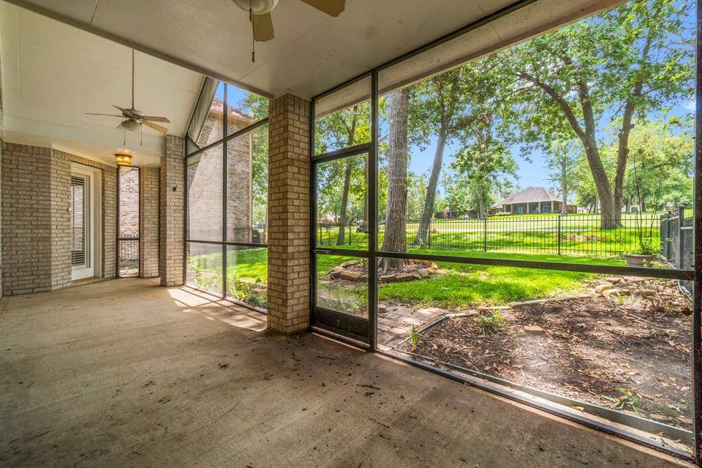This is a spacious, covered patio with a screened enclosure, offering a view of a large, fenced backyard with mature trees. Ideal for outdoor relaxation and entertainment.