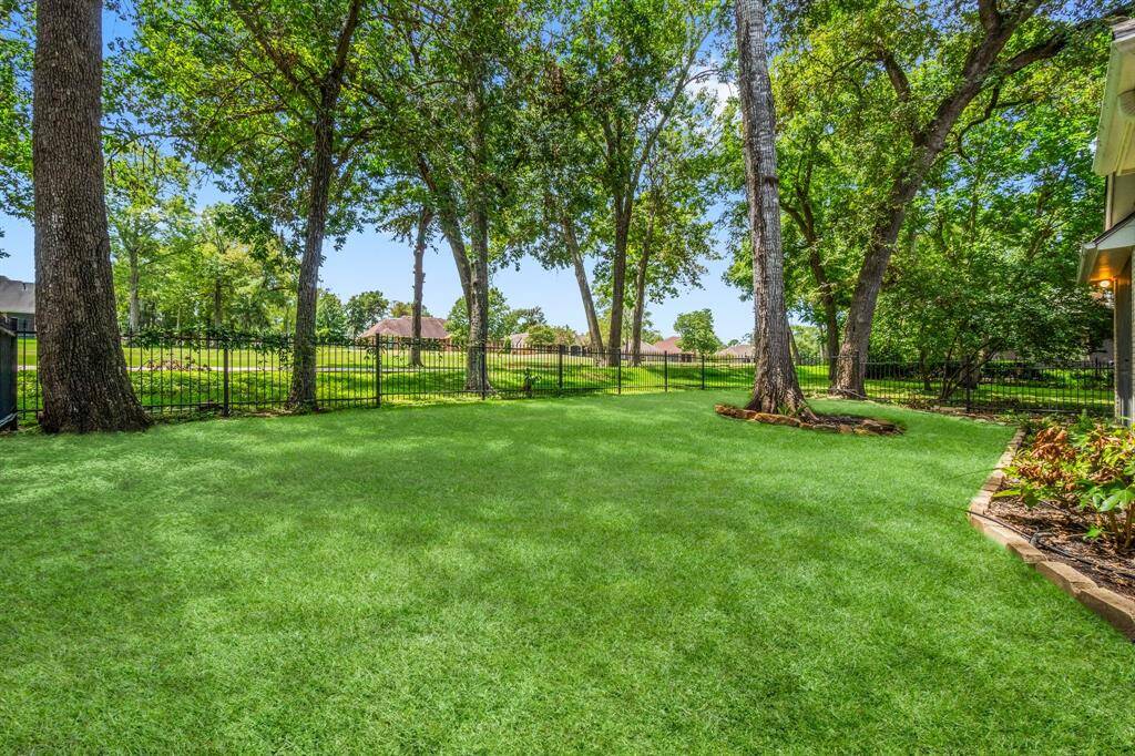 This is a well-maintained backyard with lush green grass, mature trees, and a wrought-iron fence offering a clear view of the Golf Course area. Ideal for outdoor relaxation and activities.