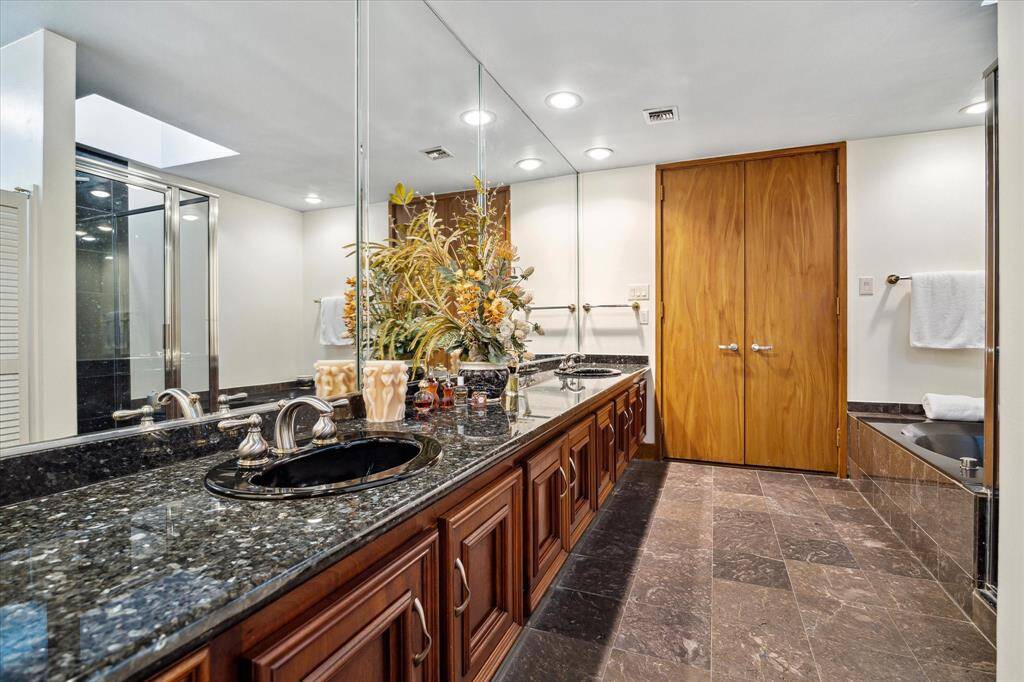 Luxurious stone-clad primary bathroom featuring dual closets for ample storage.