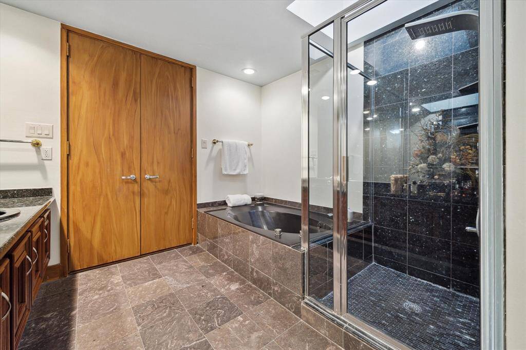 Elegant primary suite with a jetted tub and a sleek glass-enclosed shower.