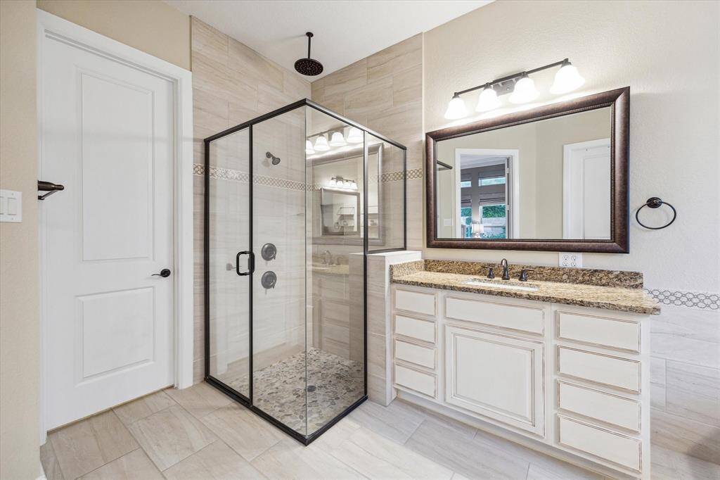 Dual head shower with gorgeous pebbled stone and tile in this amazing primary bathroom!