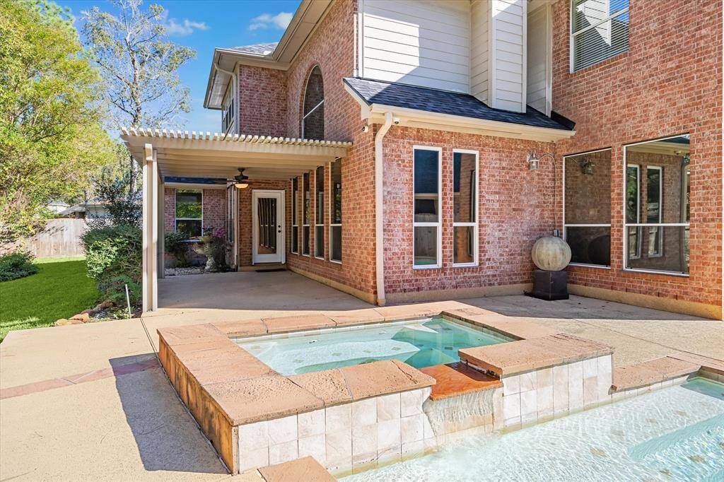 This photo showcases a well-maintained backyard with a covered pergola, sprinkler system and a view of a pool. No neighbors directly behind all adding to a serene outdoor living space ideal for relaxation and entertainment.