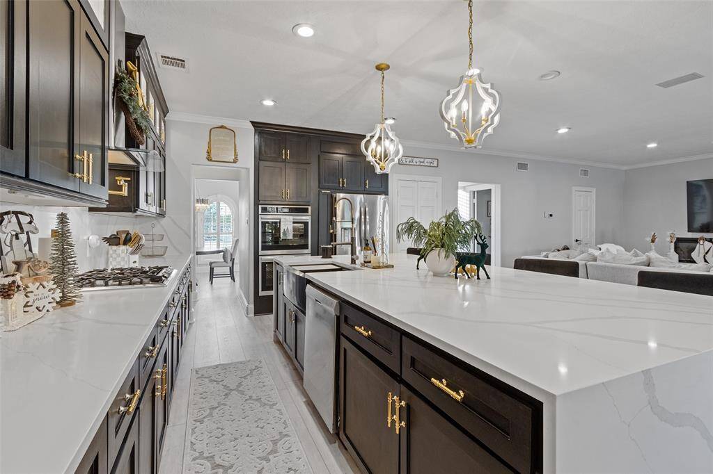 Another stunning view of this magnificent kitchen that flows beautifully into the open living area creating a  sophisticated and inviting space.  Cabinets have been painted a tan color recently.