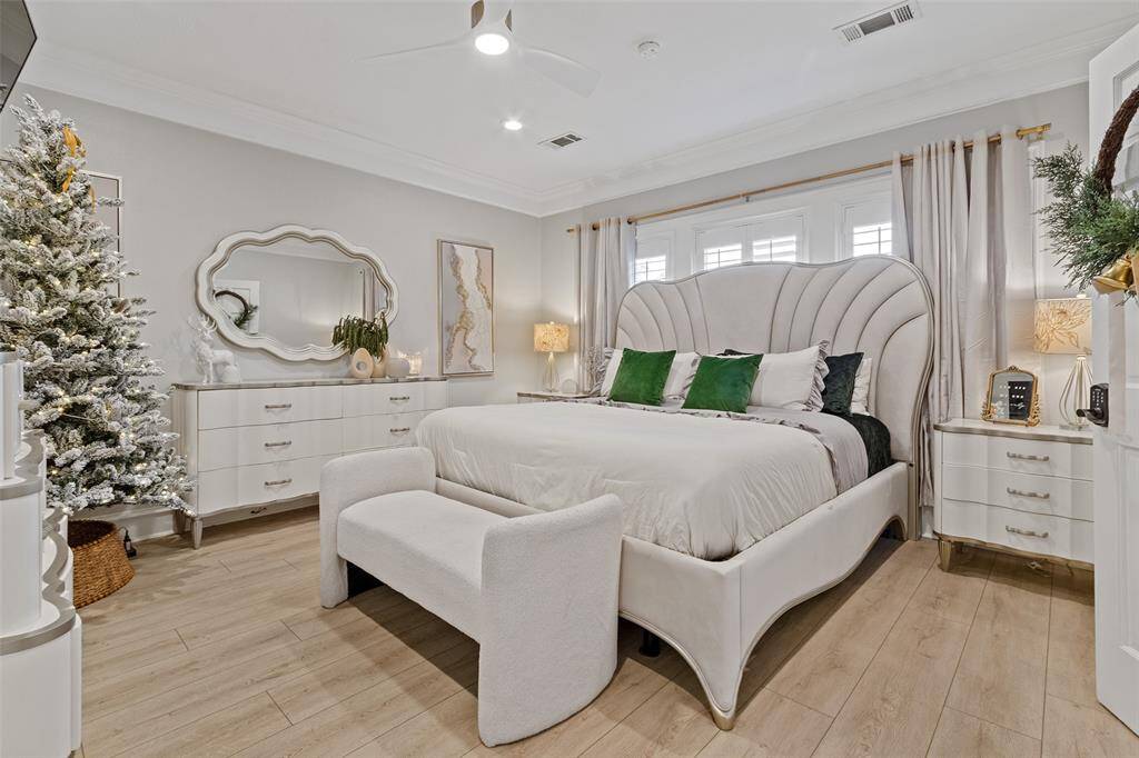 Experience the elegance of the primary bedroom that is complete with wood floors, a wall of windows, and a fashionable ceiling fan.