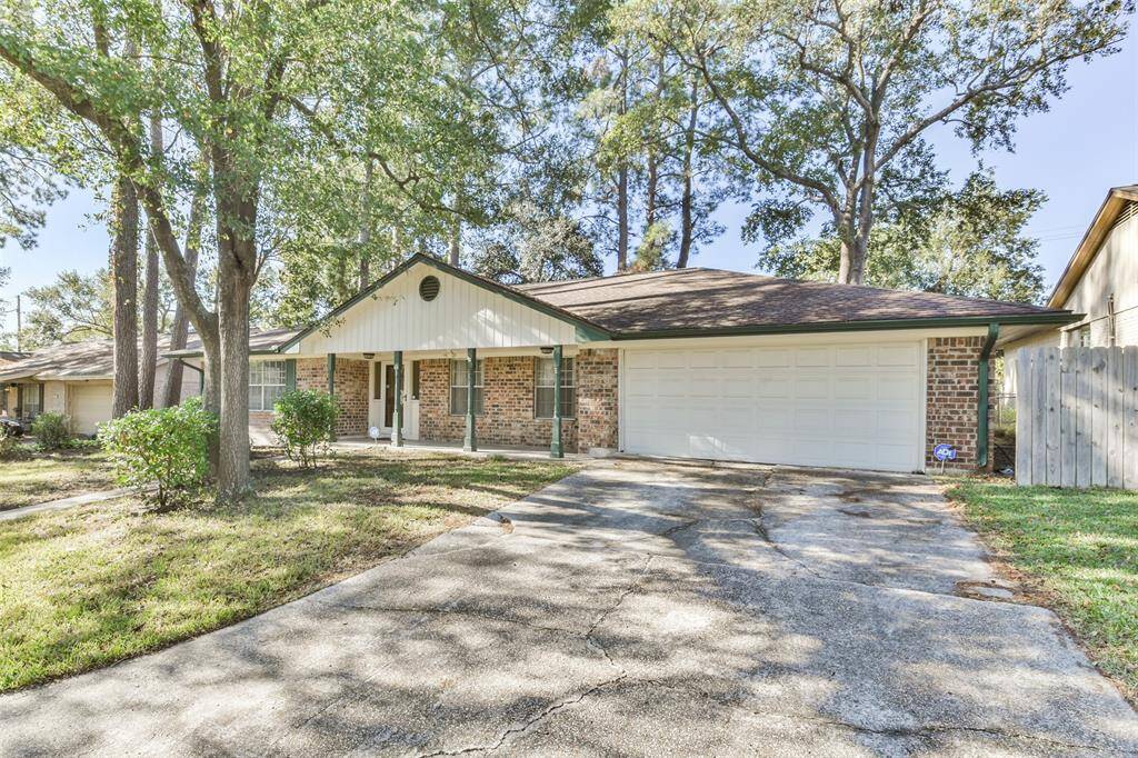 Charming brick-front home with a welcoming covered porch, nestled among mature trees. The extended driveway leads to a two-car garage, offering ample parking and convenience.