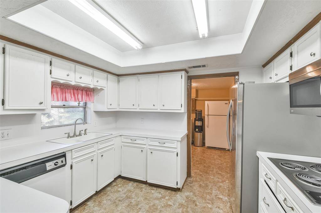 Well-lit kitchen with white cabinetry and countertops, offering abundant storage and prep space