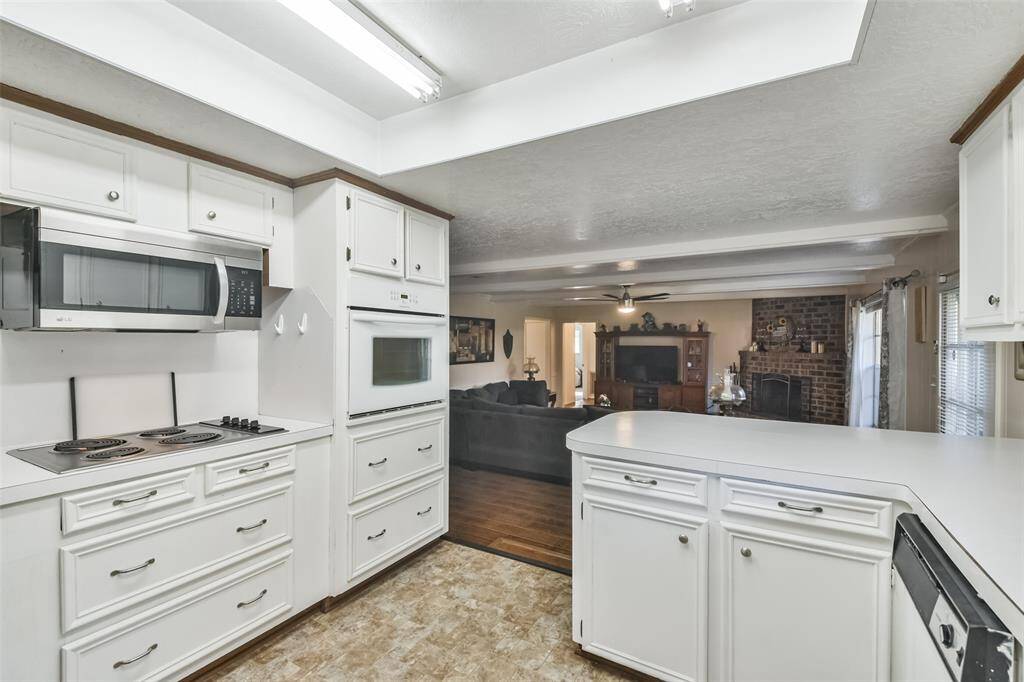 Functional kitchen with built-in appliances, including a microwave, oven, and cooktop, complemented by white cabinetry and plenty of counter space. The open design offers clear views into the living room, creating a seamless flow for entertaining and everyday living