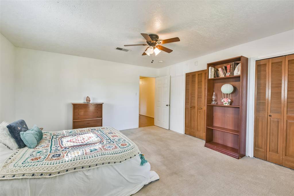 This generously sized third bedroom offers ample space for both relaxation and functionality. Featuring soft carpeting, and dual closets for abundant storage, it is ideal for a variety of uses. The large layout underscores the spaciousness found throughout the home’s bedrooms