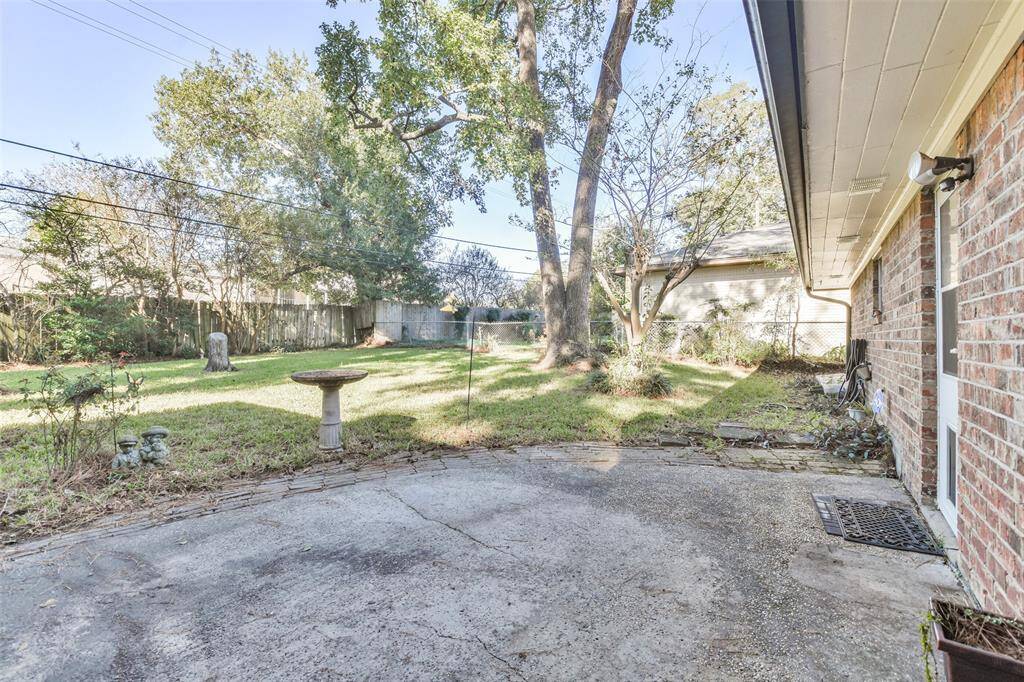 Expansive backyard featuring a spacious patio and a well-maintained lawn surrounded by mature trees and a privacy fence. This serene outdoor area is perfect for relaxation, gardening, or entertaining guests in a natural setting.