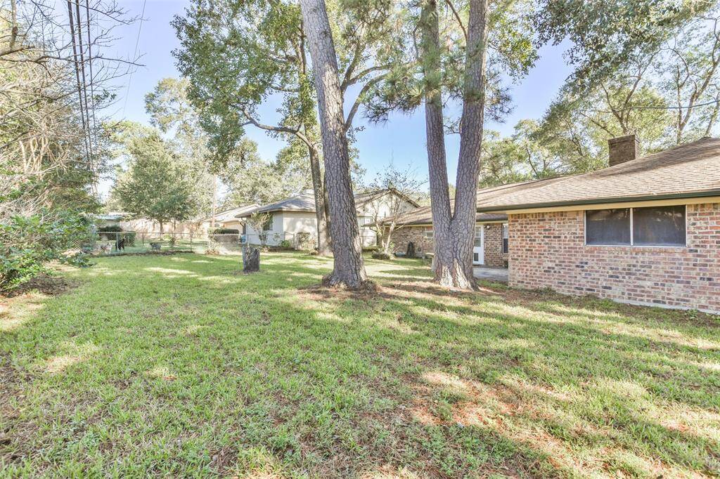 Beautiful backyard with a spacious lawn and mature trees providing shade and privacy. The natural landscaping creates a serene setting, perfect for outdoor gatherings, relaxation, or play. The brick exterior of the home adds to the timeless charm of this inviting space.