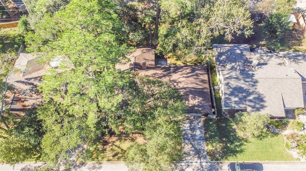 An aerial view of 1805 Twila Lane highlights the expansive tree-covered lot, offering privacy and shade. This home is nestled in a peaceful neighborhood, with its spacious yard and charming curb appeal standing out.