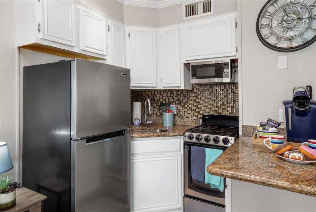 The kitchen includes granite countertops, a built-in microwave, a stove, and a refrigerator. Start your day with coffee or breakfast at the beautiful breakfast bar.