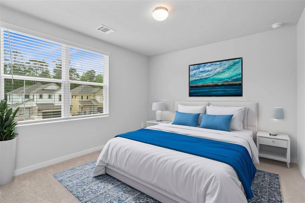 This secondary bedroom features high ceilings, lighting, custom paint, plush carpet, ample closet space, and  large windows with blinds!