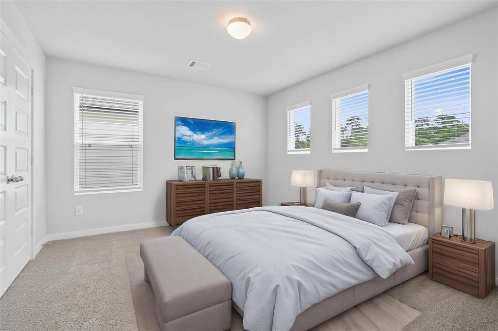 This secondary bedroom features high ceilings, lighting, custom paint, plush carpet, ample closet space, and plenty of windows with blinds allowing in natural lighting!