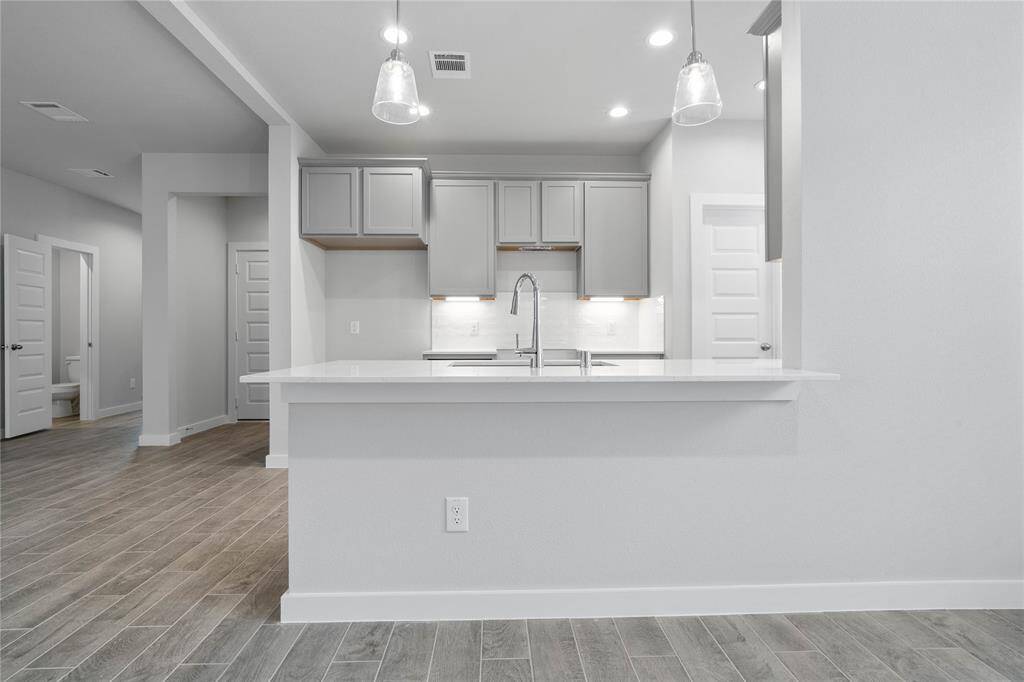Any chef's dream, this stunning kitchen is perfect for everyday life as well as entertaining family and friends! This kitchen features stained cabinets, quartz countertops, extended countertop for breakfast bar, high ceilings with recessed and pendant lighting, and a pantry!
