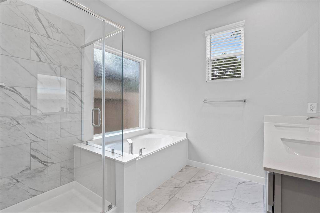 Additional view of the primary bathroom features dark framed walk-in shower with tile surround, and separate garden tub for soaking after a long day with custom tile detailing!