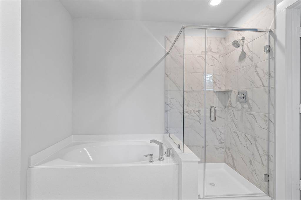 Additional view of the primary bathroom featuring the framed walk-in shower with tile surround, and separate garden tub for soaking after a long day!
