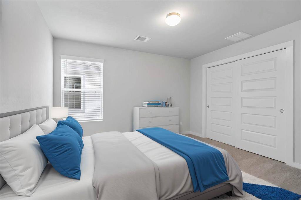 This secondary bedroom features high ceilings, light, custom paint, plush carpet, ample closet space, and a large window.