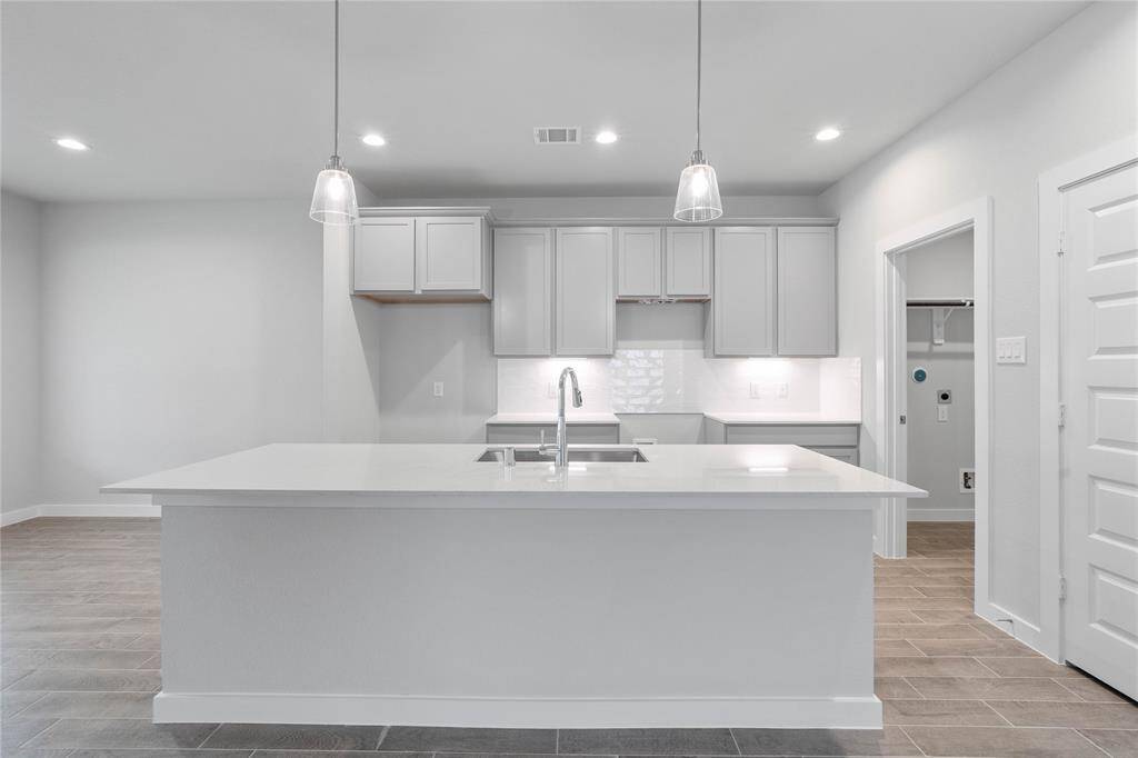 Any chef's dream, this stunning kitchen is perfect for everyday life as well as entertaining family and friends! This kitchen features stained cabinets, quartz countertops, kitchen island with extended countertop for breakfast bar, high ceilings with recessed and pendant lighting, under cabinet lighting, and a pantry!