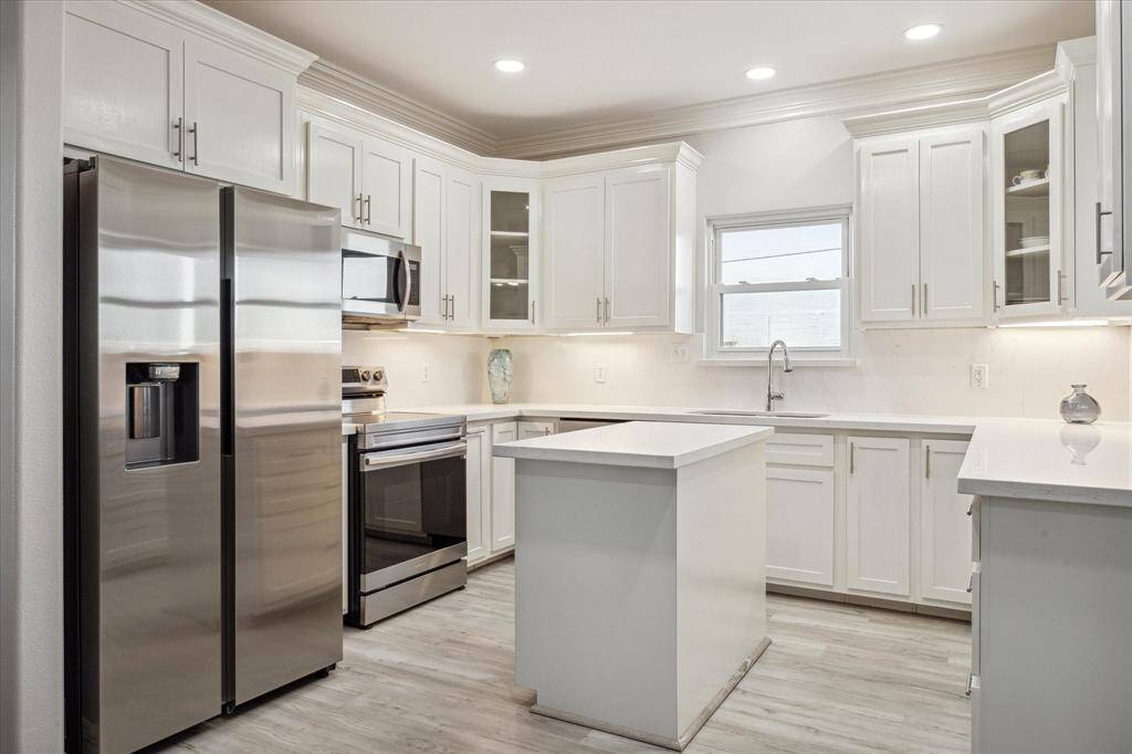 Absolutely stunning, fully remodeled kitchen, including new cabinetry, quartz counters, stainless steel appliances, and the window over the kitchen sink, looking out to the bay.