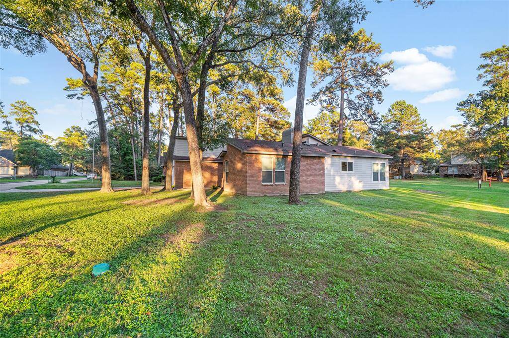 This photo showcases a charming brick and siding home set on a spacious green belt lot, grassy lot with mature trees, providing a serene and natural setting. The neighborhood appears quiet and well-maintained, ideal for privacy and relaxation.