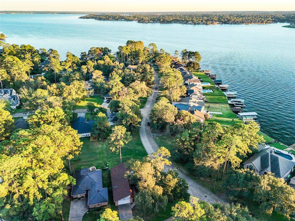 This aerial photo showcases a picturesque lakeside community with homes nestled among lush trees, featuring a scenic view of the expansive lake. Ideal for buyers seeking a tranquil waterfront lifestyle.